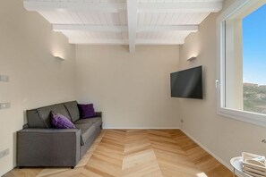 A modern living room with a sofa, a flat-screen TV mounted on the wall, and a large window offering a view. - [Residenza la Guercia]Seaview-5 terre-A/C (La Spezia)