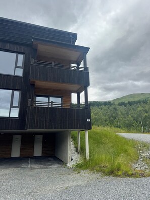 Un bâtiment moderne à deux étages, doté d’un balcon, de grandes fenêtres et offrant une vue sur un paysage verdoyant.