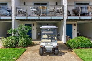 A golf cart parked in front of a building with a covered entrance and a balcony with chairs. - Beachfront Villa with Sea Views  Bikes Included  Gulf Across St   Kayak Access (Miramar Beach)
