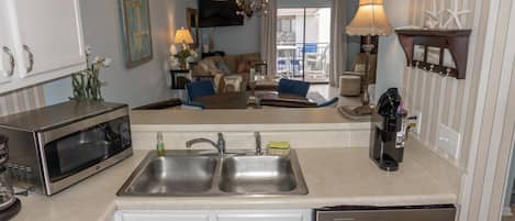 A kitchen with a double sink, a microwave, and a coffee maker.