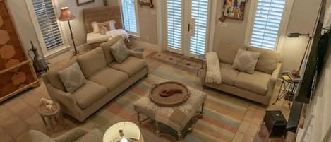 A spacious living room with a large sofa, a smaller sofa, a coffee table, and a staircase leading to an upper level.