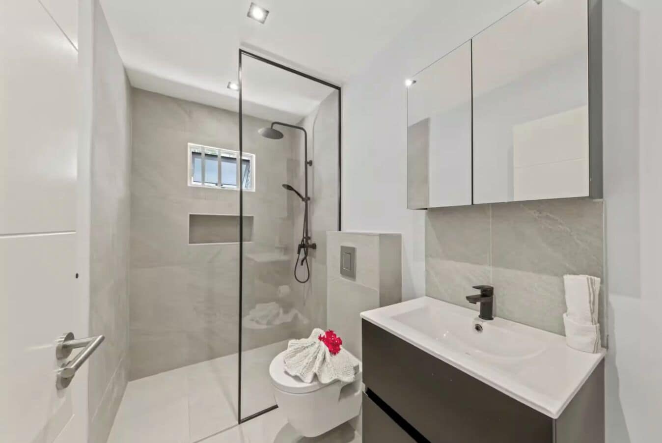 A modern bathroom with a glass shower enclosure, a white sink, and a large mirror.