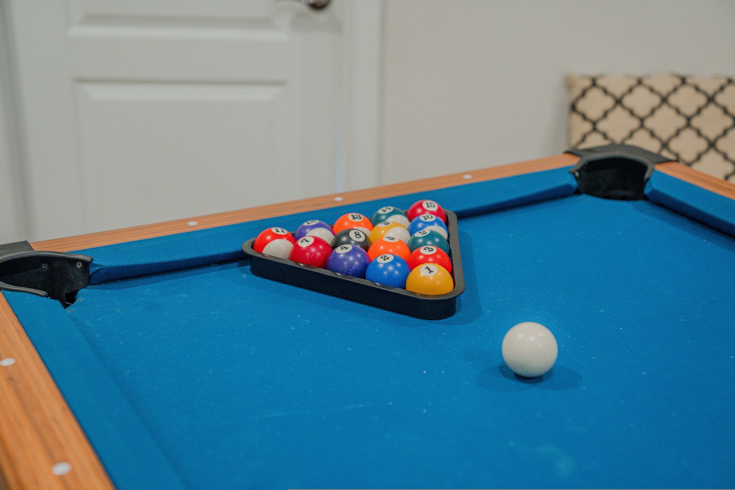 A pool table with a rack of numbered balls and a cue ball.