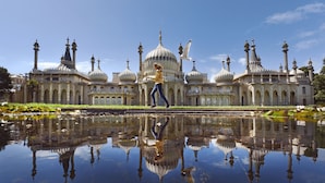 A large building with multiple domes and towers, a reflective water surface in front, and a person walking. - Woodland View 2 By My Getaways (Brighton)