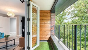 A balcony with a glass door, wooden wall, and a view of trees. - Woodland View 2 By My Getaways (Brighton)