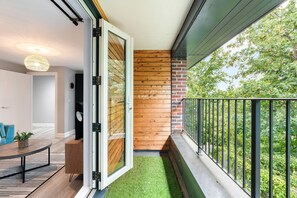 A balcony with a glass door, wooden wall, and a view of trees. - Woodland View 2 By My Getaways (Brighton)