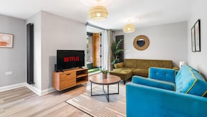 A modern living room with a flat-screen TV, a sofa, a coffee table, and a large window. - Woodland View 2 By My Getaways (Brighton)