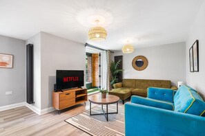 A modern living room with a flat-screen TV, a sofa, a coffee table, and a large window. - Woodland View 2 By My Getaways (Brighton)