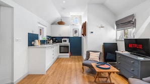 Un espacio habitable compacto con kitchenette, comedor y sala de estar con televisor.