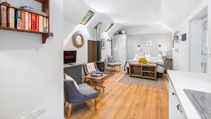Un interior moderno con un dormitorio tipo loft, una sala de estar con chimenea y una estantería llena de libros.
