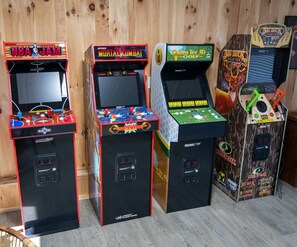Vier speelautomaten met verschillende spellen, waaronder NBA Jam, Mortal Kombat, Golden Tee 3D en Big Buck Hunter.