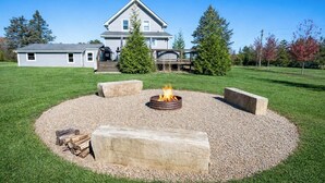 A house with a fire pit in the backyard surrounded by stone seating and a gravel area.