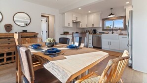 A modern kitchen with white cabinets, a dining table with blue plates, and a wooden chair.