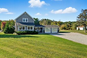 A two-story house with a covered porch, a driveway, and a well-maintained lawn.