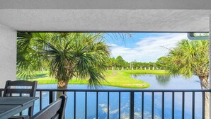 Een balkon met uitzicht op een golfbaan, een waterpartij en een verafgelegen landschap.