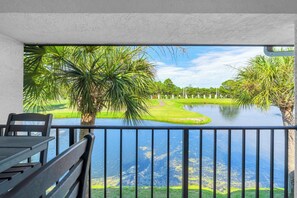 Ein Balkon mit Blick auf einen Golfplatz, ein Gewässer und eine entfernte Landschaft.