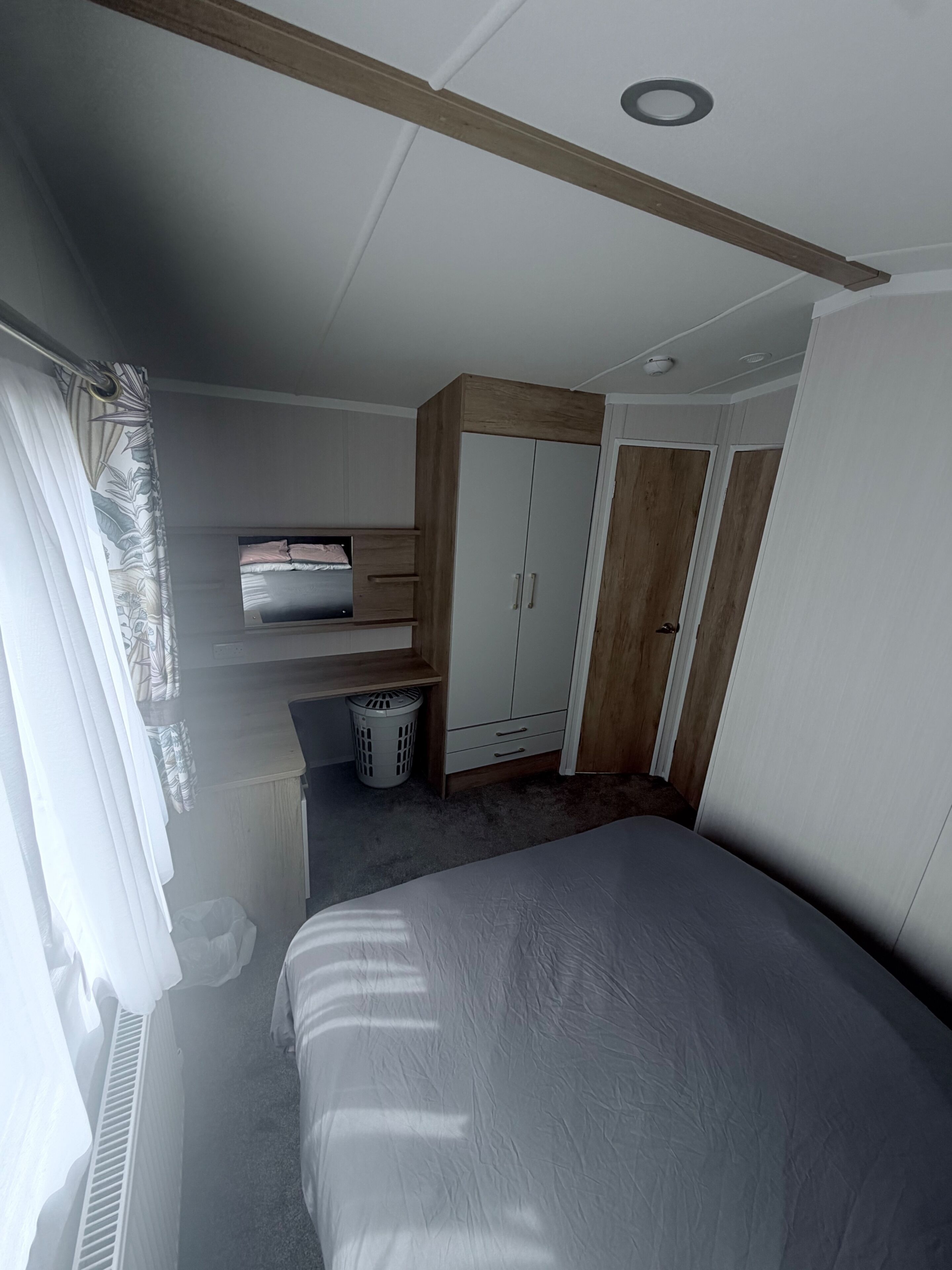 Une chambre à coucher avec un lit, une armoire et un téléviseur posé sur un meuble.