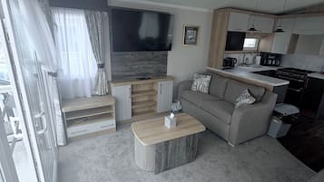 Una sala de estar moderna con un sofá, una mesa de centro y un televisor montado en la pared.