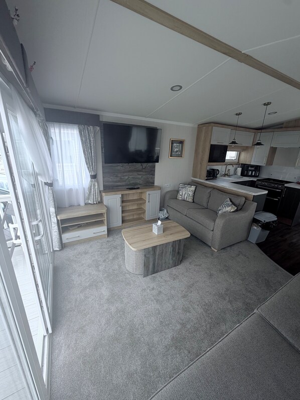 A modern living room with a sofa, coffee table, and a TV mounted on the wall. - Coastfields 8 Berth Holiday Home (Skegness)