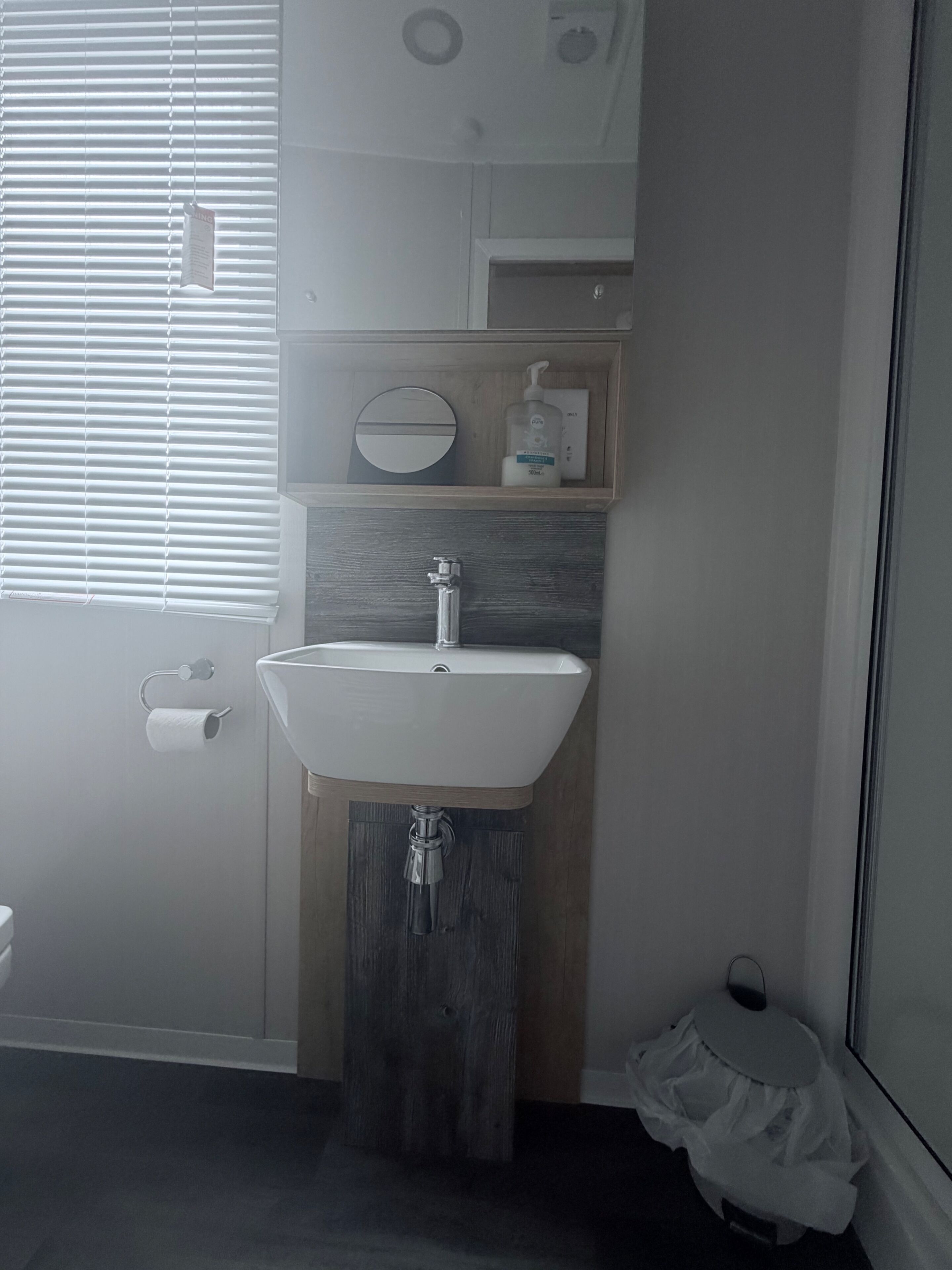 Une salle de bain avec un lavabo blanc, un meuble-lavabo en bois et des toilettes.