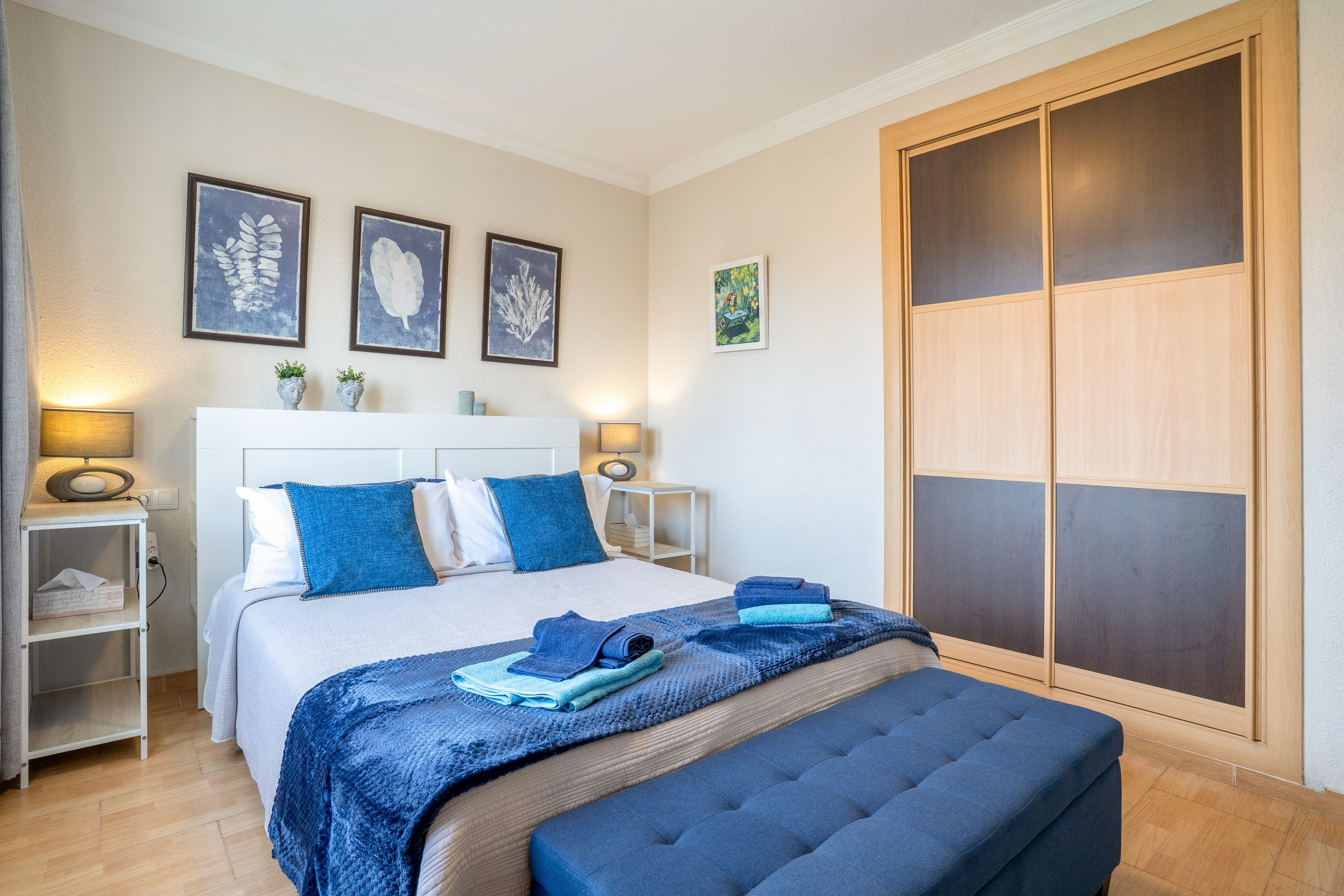 Une chambre à coucher avec un lit, des tables de chevet, une armoire et des œuvres d’art accrochées au mur.