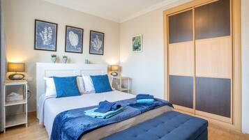 Une chambre à coucher avec un lit, des tables de chevet, une armoire et des œuvres d’art accrochées au mur.