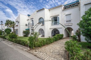 A white building with multiple windows and balconies, a paved driveway, and surrounding greenery. - Balcón Pueblo Andaluz Apartment with Sea Views, Wi-Fi and Air Conditioning (Torrox)