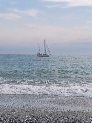 A calm sea with a sailboat anchored in the distance.
