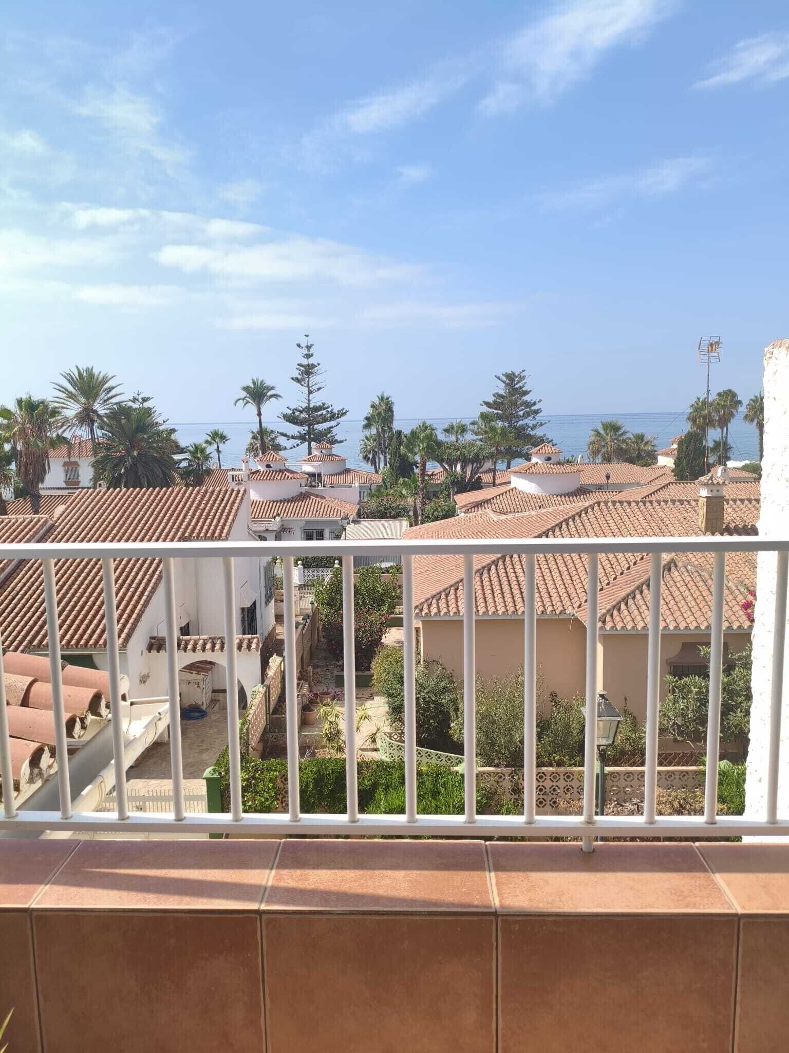 Un balcón con vista a edificios con tejas de barro y palmeras.