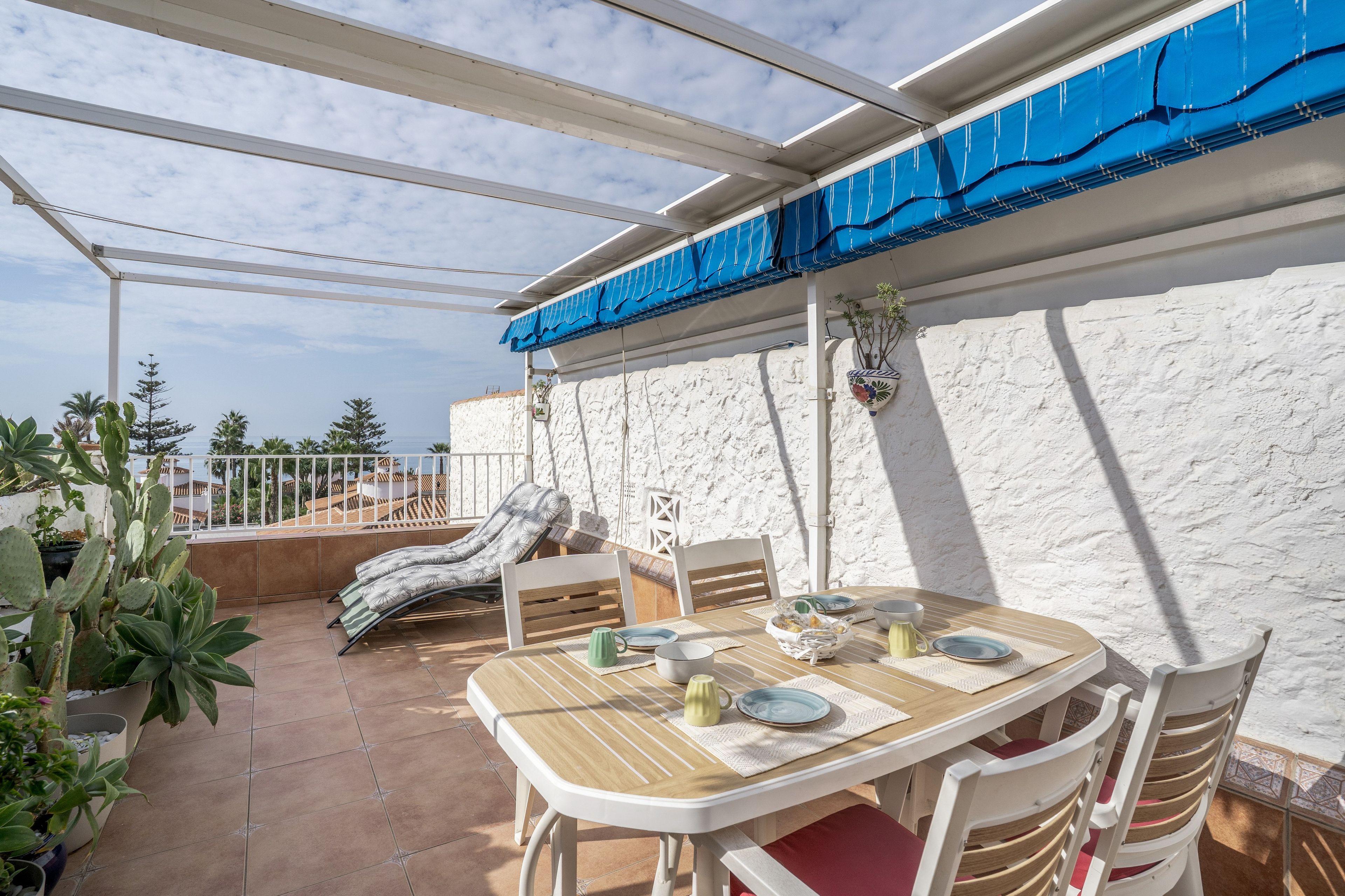 Eine Terrassengaststätte mit Esstisch, gepolstertem Stuhl und Blick aufs Meer.