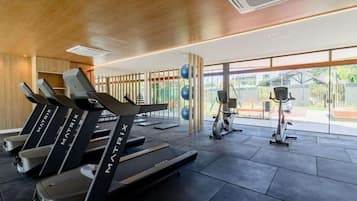 Uma academia com esteiras, bicicletas ergométricas e bolas de exercício.