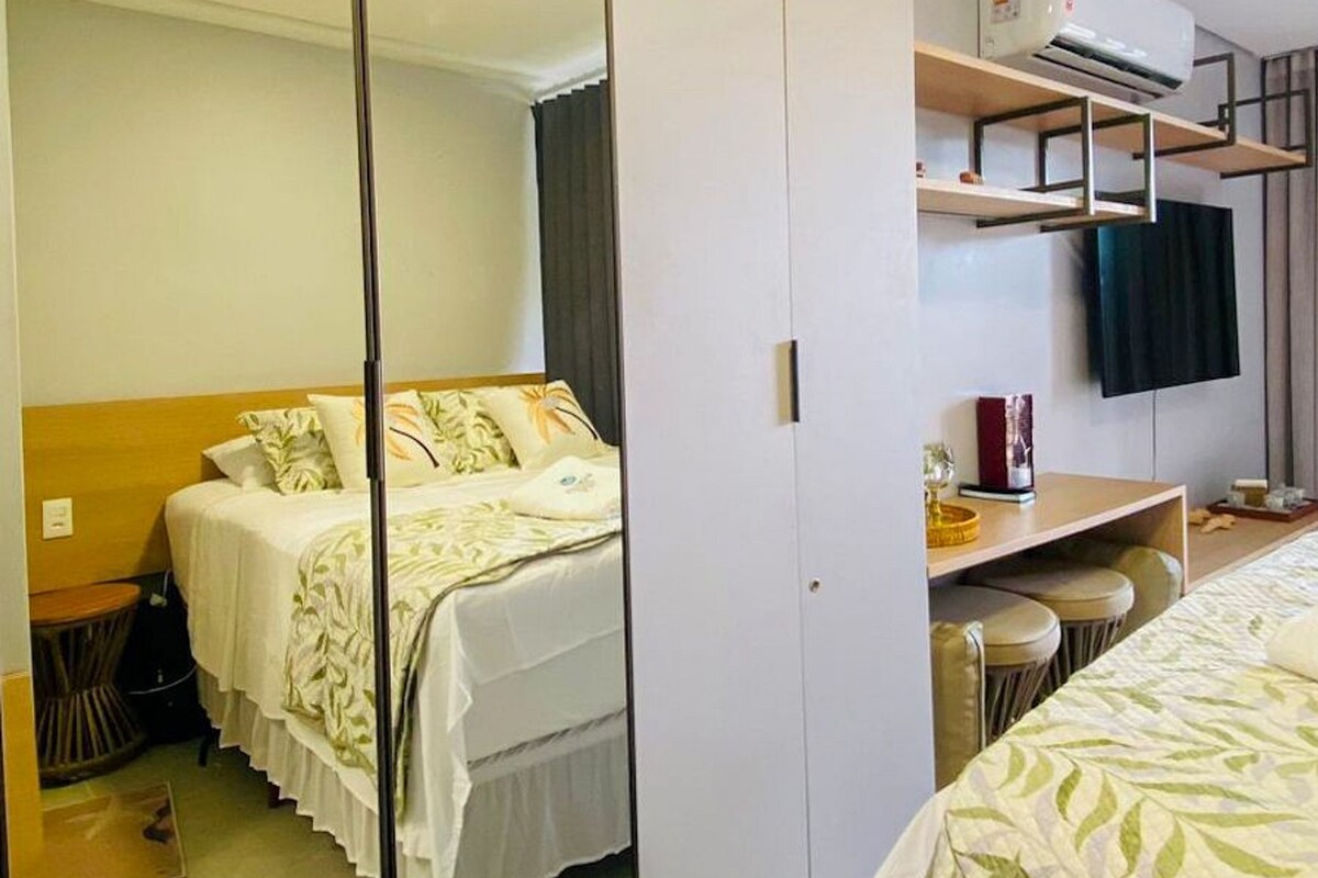 A bedroom with a bed, a wardrobe, a TV, and a desk.