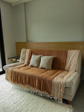 A modern living room with a sofa, a throw blanket, and a patterned throw. - Beach Class Solare por YOLO (Ipojuca)