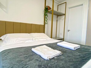A hotel room with a bed, a towel, a hanging plant, and a wardrobe. - Beach Class Solare por YOLO (Ipojuca)