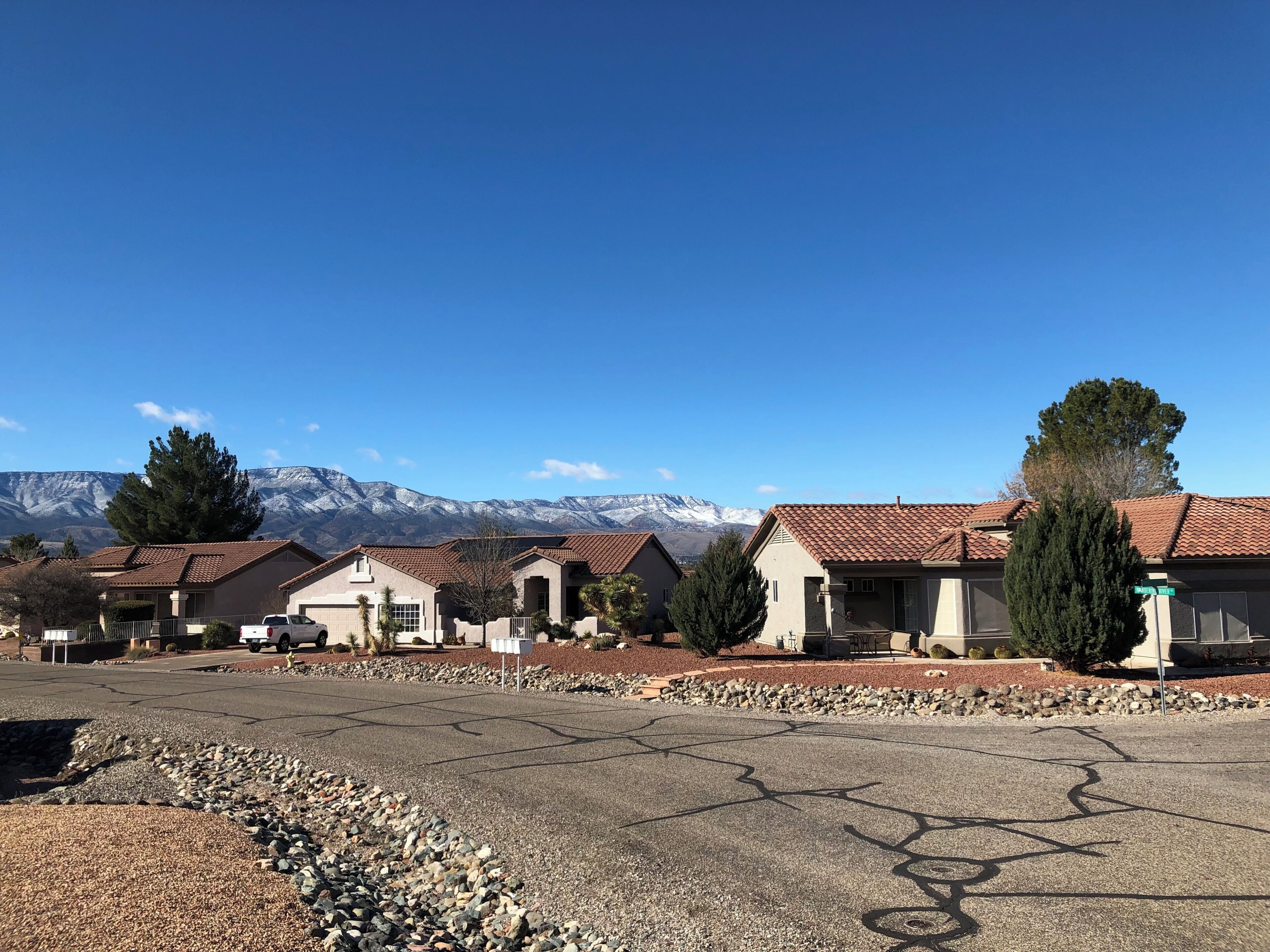Un quartier résidentiel avec des maisons, un ciel dégagé et des montagnes en arrière-plan.