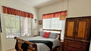 A bedroom with a wooden bed, a dresser, and a window with blinds. - The Jewel near Sedona (Cornville)