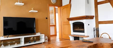 A living room with a television, fireplace, wooden beams, and a patterned rug.