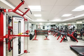 A gym with red and black exercise equipment, a mirrored wall, and a variety of weight machines.