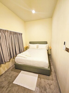 Ein Hotelzimmer mit Bett, Vorhängen, Nachttisch und einer Steckdose.