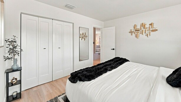 Une chambre à coucher comprenant un lit, une armoire, un miroir et un luminaire fixé au mur.