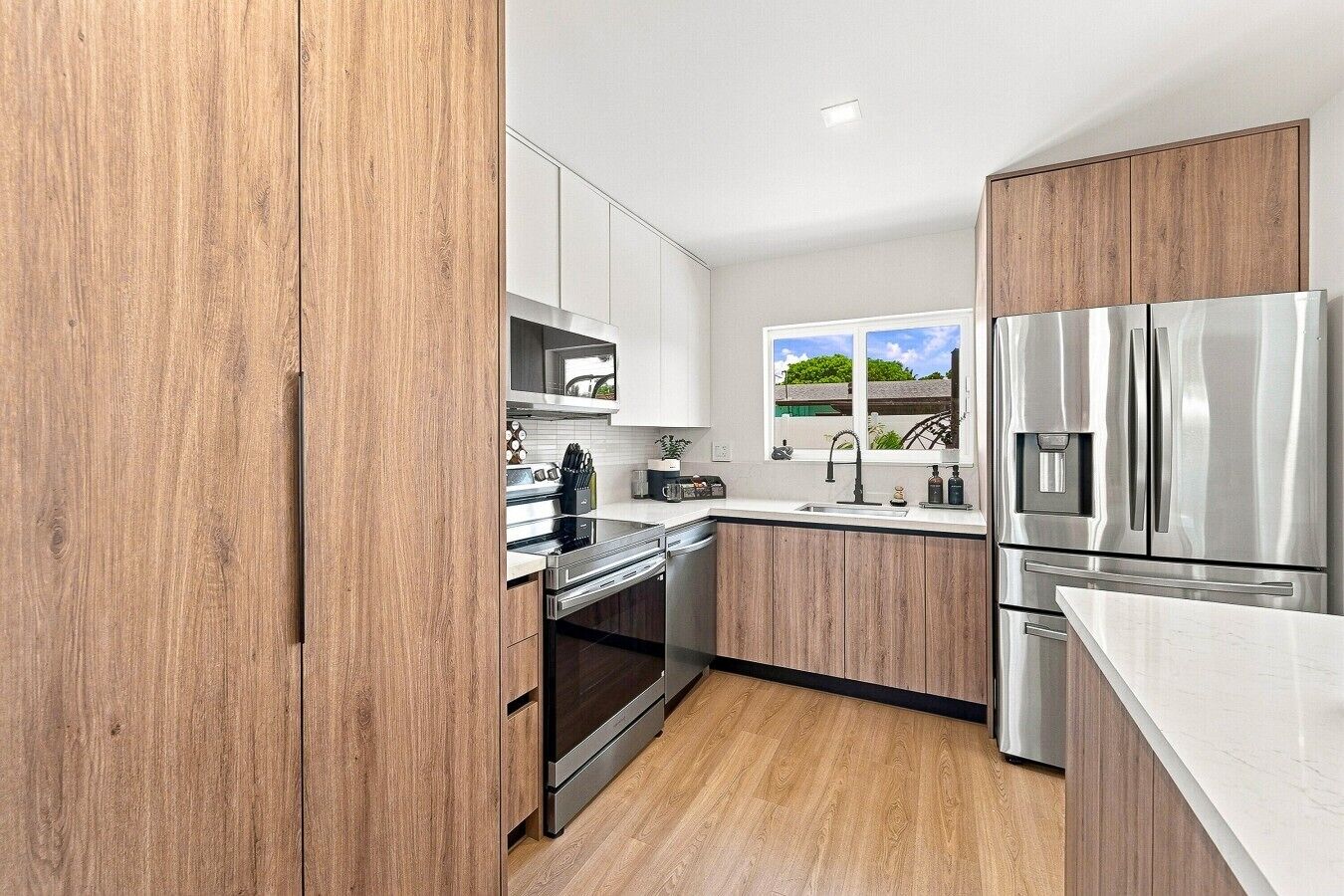 A modern kitchen with wooden cabinets, stainless steel appliances, and a window with a view.