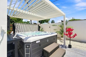 A hot tub under a white pergola, surrounded by a white fence, with a bench and a potted plant nearby. - Spa Hot Tub | Mins to Beach | 2 Kings | Brand New! (Pompano Beach)
