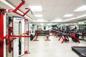 A gym with red and black exercise equipment, a mirrored wall, and a variety of weight machines. - NYC | Midtown Manhattan | Skyline Views | 2BR Presidential (NEW YORK)