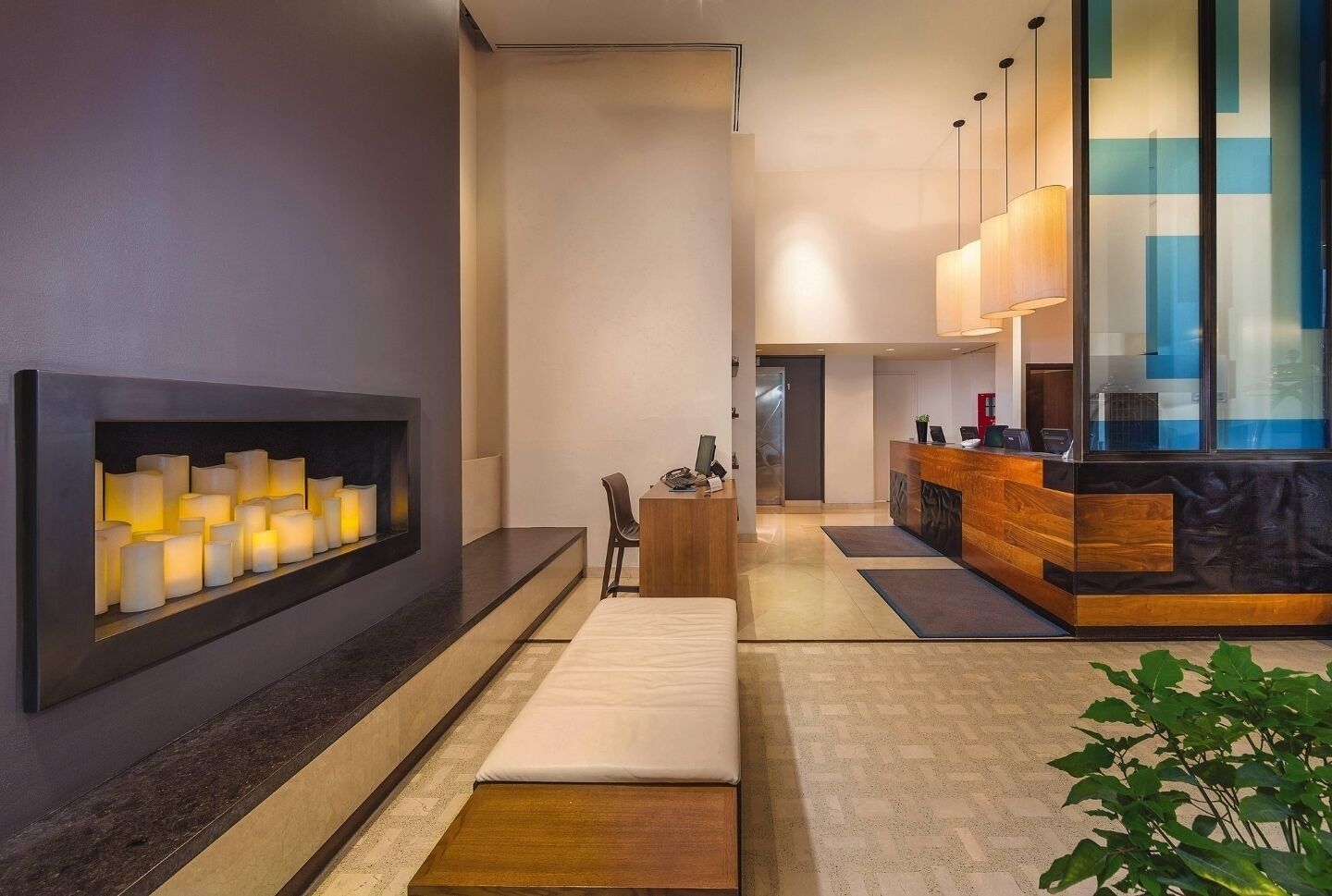 A modern hotel lobby with a reception desk, a seating area, and a wall-mounted light fixture.