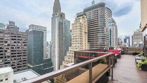 A rooftop terrace with a view of the city skyline, including a prominent skyscraper.