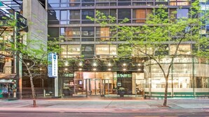 A modern hotel with a glass facade, outdoor seating area, and a sign indicating 'Wyndham' branding.