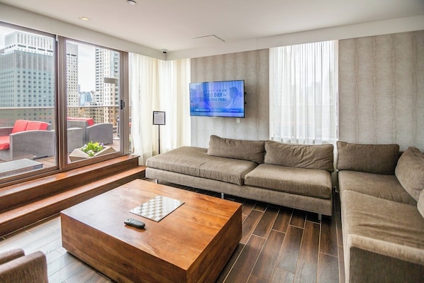 A modern living room with a sofa, a coffee table, and a TV mounted on the wall.
