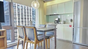 A modern kitchen with a dining area, a coffee maker, and a stainless steel refrigerator.