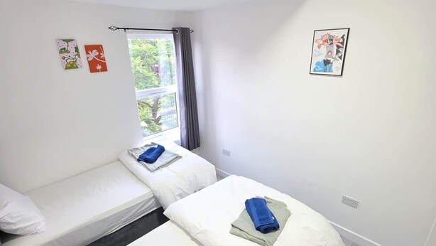 Een hotelkamer met twee eenpersoonsbedden, een raam met gordijnen en een plafondlamp.