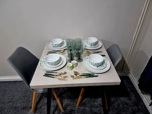A dining table set with plates, bowls, glasses, and cutlery. - Cosy Modern Flat by Etihad Stadium & Co-op Live (Manchester)